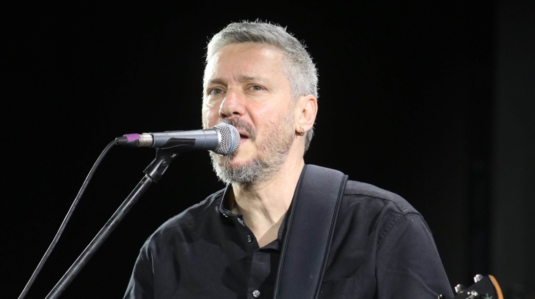 Ο Αλκίνοος Ιωαννίδης μπροστά στο μικρόφωνο με την κιθάρα στο χέρι