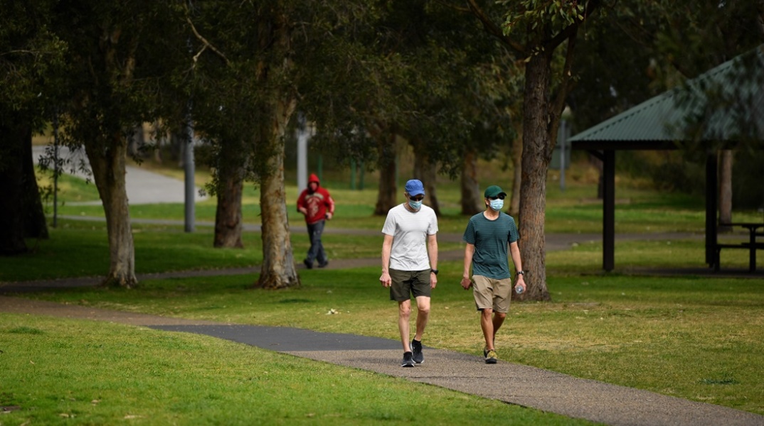 Πολίτες με μάσκα προστασίας και αθλητικά ρούχα απολαμβάνουν τις βόλτες τους σε πάρκο στην Αυστραλία