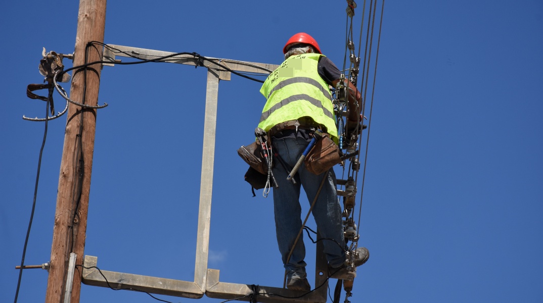 Εργαζόμενος σκαρφαλωμένος σε κολώνα της ΔΕΗ πραγματοποιεί εργασίες