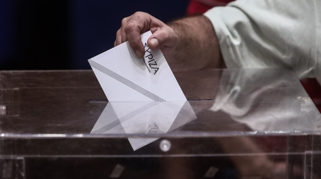 Χέρι άνδρα ρίχνει το ψηφοδέλτιο με το λογότυπο του ΣΥΡΙΖΑ σε κάλπη