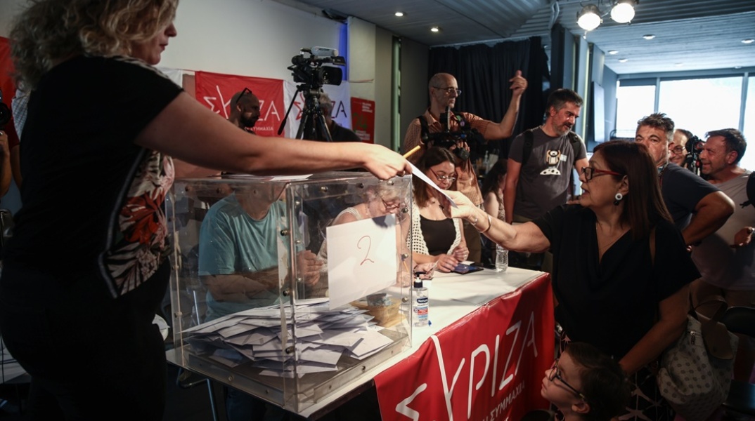 Γυναίκα με το παιδί της προσέρχονται στην κάλπη για τις εσωκομματικές εκλογές ανάδειξης νέου προέδρου στον ΣΥΡΙΖΑ