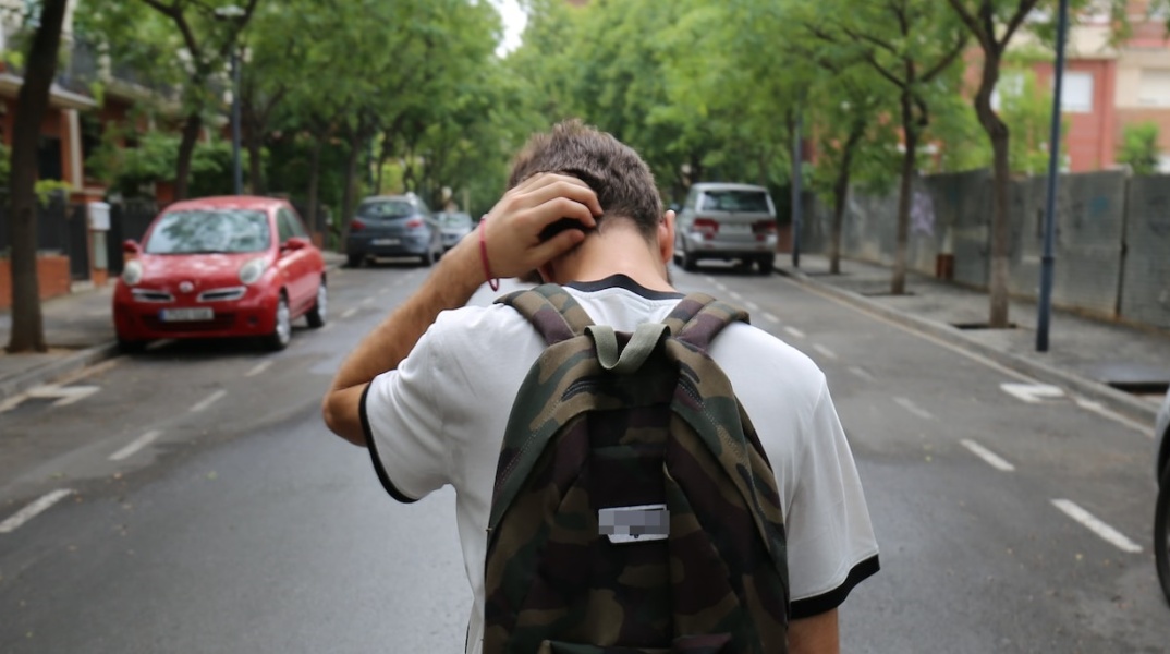 Ανήλικος μαθητής με τη σχολική του τσάντα στην πλάτη περπατά σε δρόμο κρατώντας τον αυχένα του