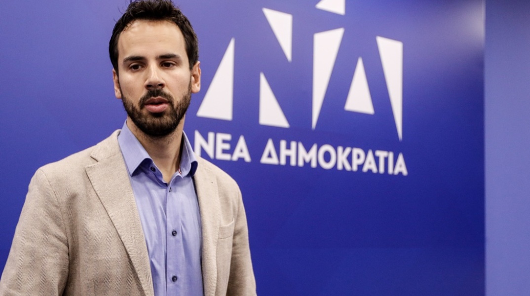 Ο Νίκος Ρωμανός μπροστά από το λογότυπο της Νέας Δημοκρατίας 