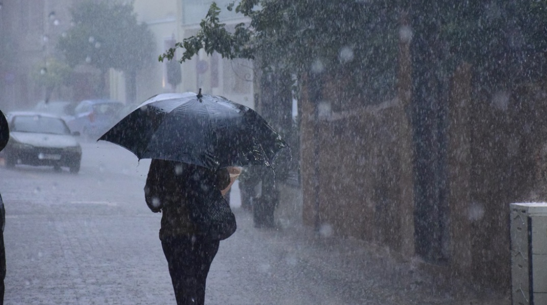 Ισχυρή καταιγίδα και γυναίκα που προσπαθεί να προστατευτεί με ομπρέλα