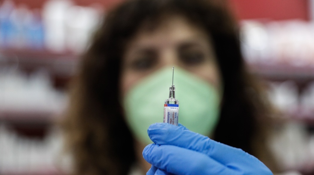 Φαρμακοποιός ετοιμάζεται να κάνει το αντιγριπικό εμβόλιο