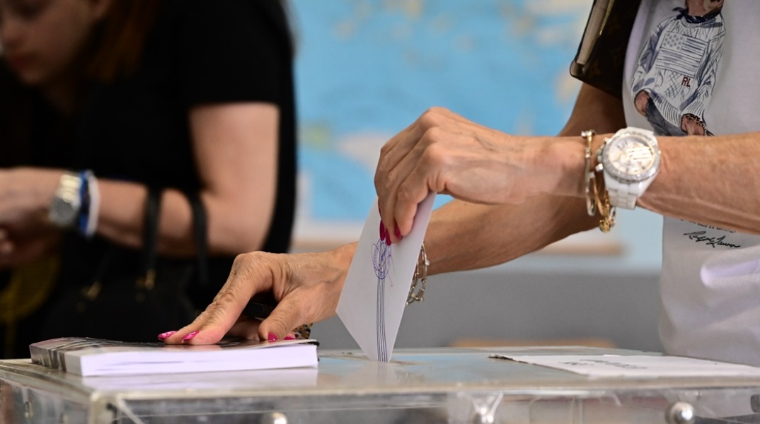 Χέρι γυναίκας ρίχνει ψηφοδέλτιο σε κάλπη