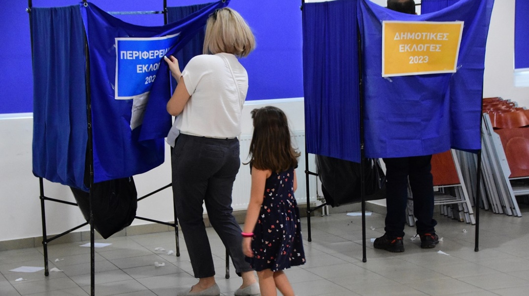Κοριτσάκι μαζί με τη μητέρα του μπαίνει σε παραβάν για να ψηφίσει στις Δημοτικές και Περιφερειακές Εκλογές 2023