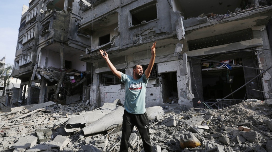 Άνδρας με υψωμένα τα χέρια φωνάζει μπροστά από συντρίμμια σπιτιού στη Γάζα