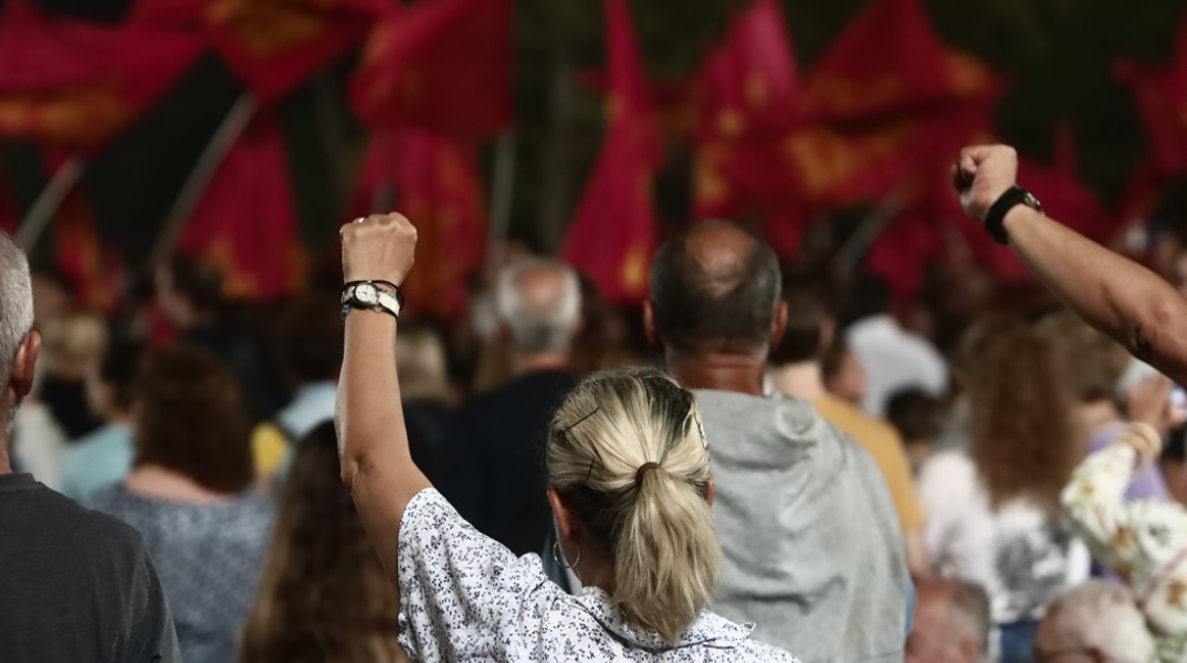 Υψωμένες αριστερές γροθιές από μέλη του ΚΚΕ και σημαίες του κόμματος
