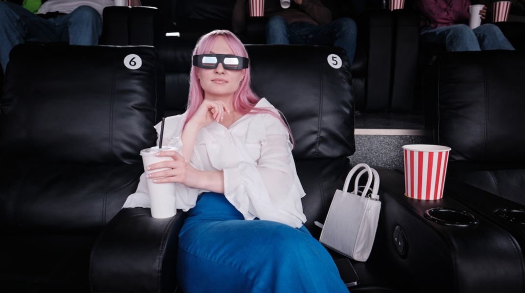 Γυναίκα με 3D γυαλιά σε αίθουσα κινηματογράφου κρατά στα χέρια της αναψυκτικό