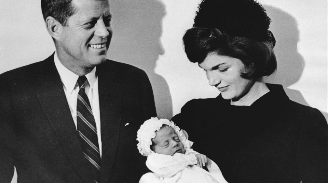 Η Τζον Φ. Κένεντι και η σύζυγός του Τζάκι, φωτογραφίζονται κρατώντας το νεογέννητο μωρό τους