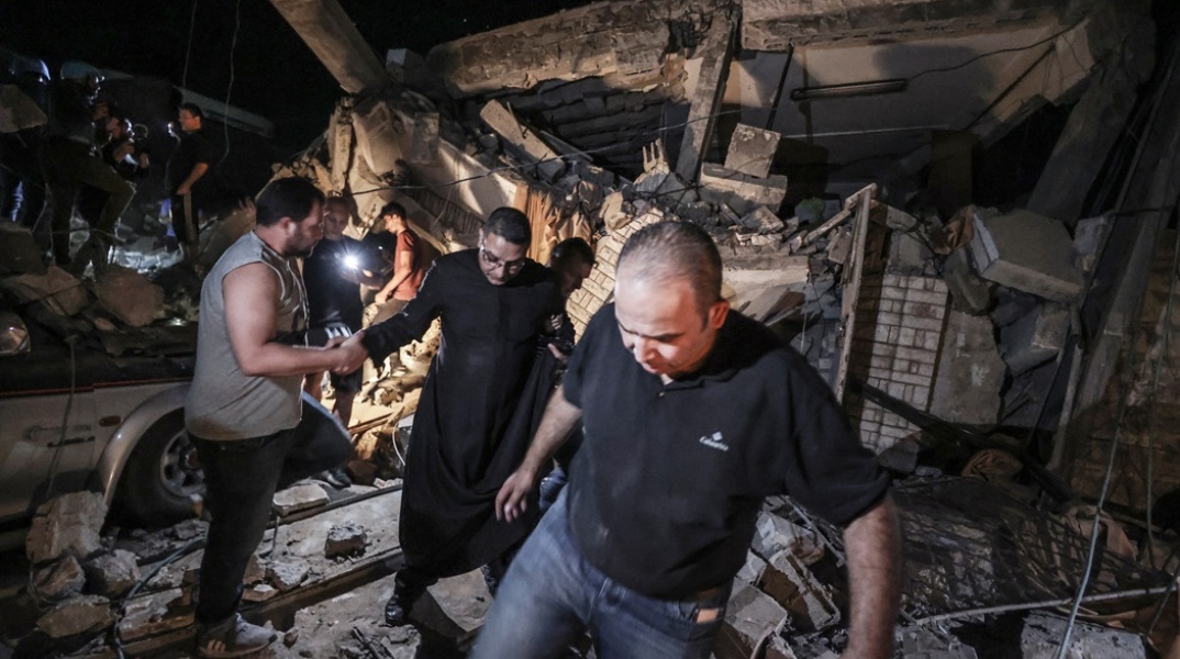 Ιερέας και πολίτες κοντά στο σημείο του βομβαρδισμού της ελληνορθόδοξης εκκλησίας στη Γάζα