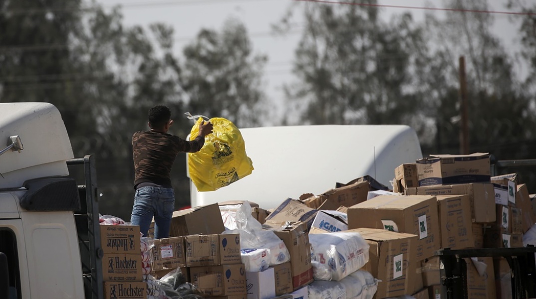 Άνδρας κρατά μία σακούλα πάνω σε φορτηγό με ανθρωπιστική βοήθεια για τη Γάζα