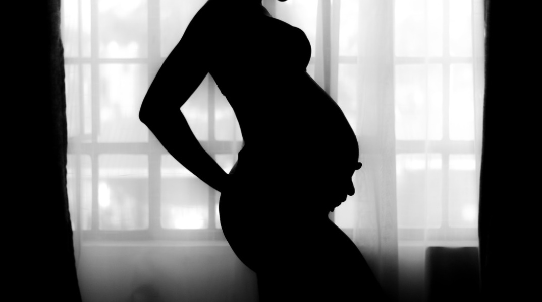 Σκιά εγκύου που κρατά τρυφερά τη φουσκωμένη της κοιλιά