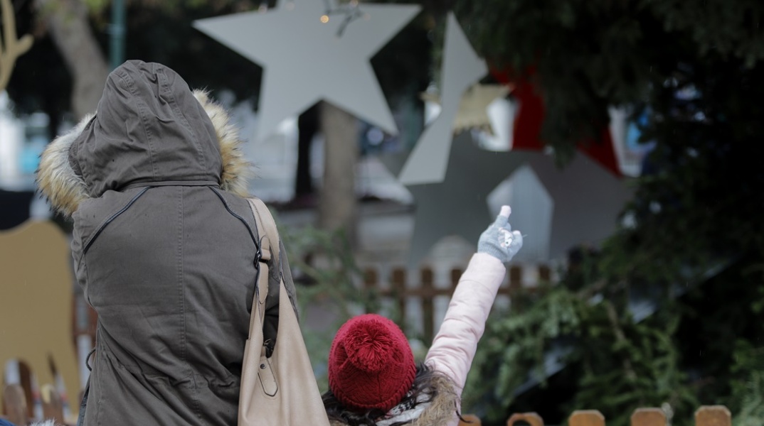 Γυναίκα με το παιδί της φορούν ζεστά ρούχα, παλτό και σκούφο για να προστατευτούν από το κρύο