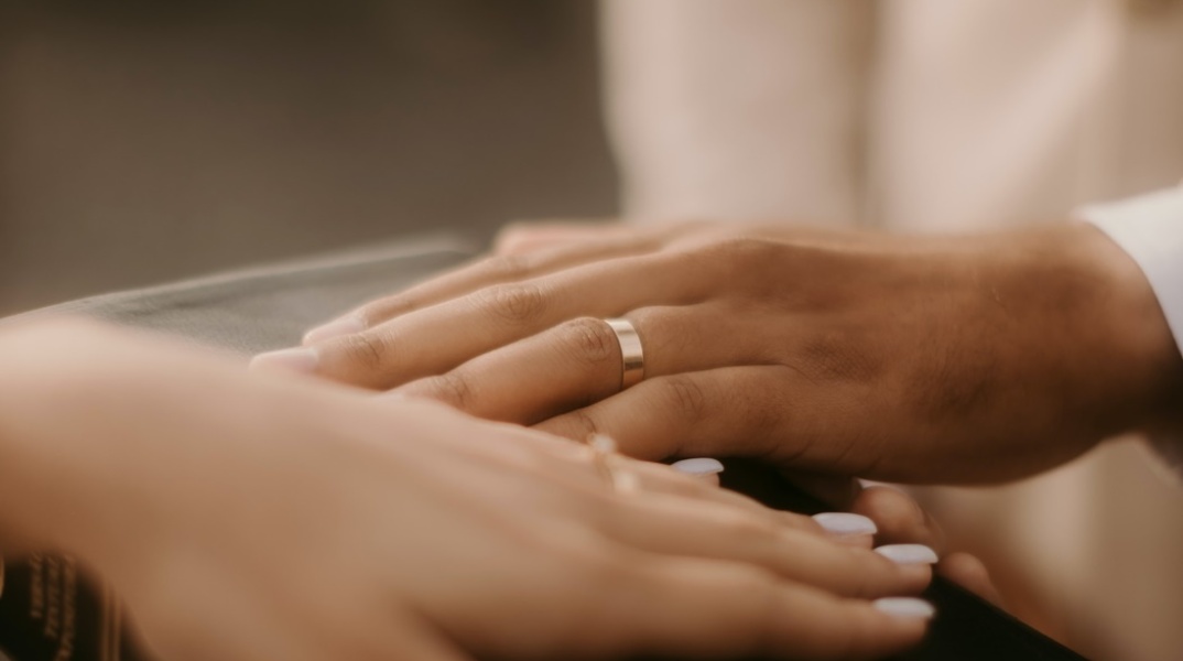 Χέρι γαμπρού και νύφης με τις βέρες