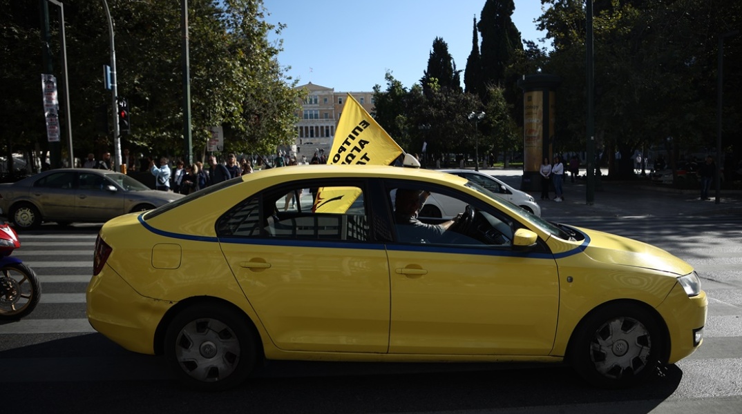 Απεργία ταξί: Οδηγός στο κέντρο της Αθήνας με σημαία κατά τη διάρκεια απεργίας