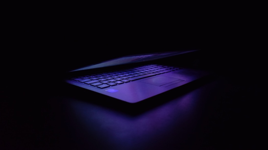 Λάπτοπ σε σκοτεινό δωμάτιο το οποίο φωτίζει μόνο η αναμμένη οθόνη