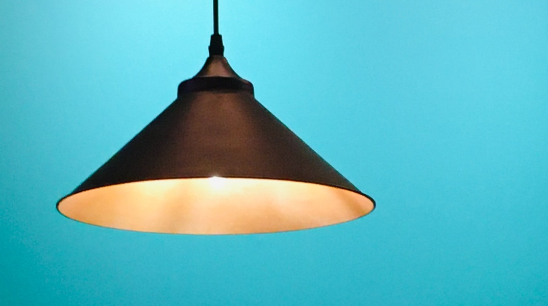 Λάμπα που κρέμεται μέσα σε φωτιστικό από το ταβάνι σε μπλε φόντο