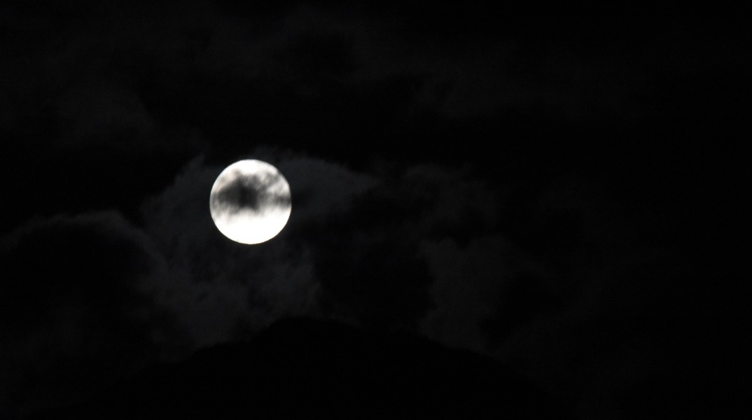 Η πανσέληνος Δεκεμβρίου πίσω από σύννεφα στον χριστουγεννιάτικο ουρανό 