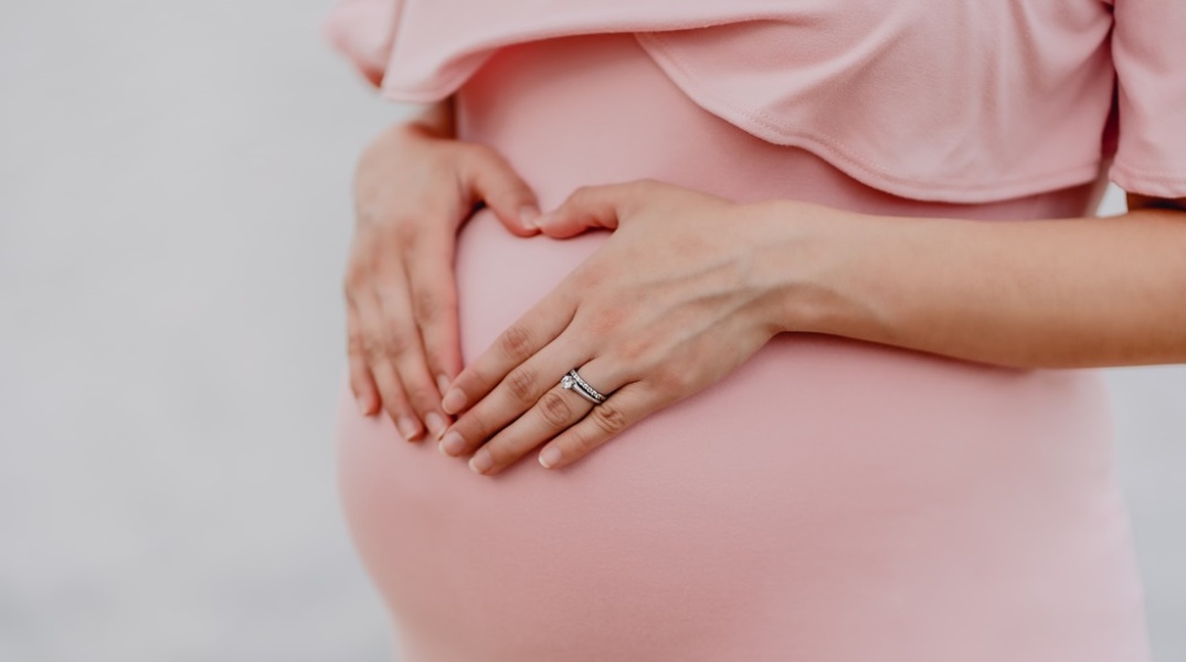 Έγκυος γυναίκα κρατά τρυφερά την κοιλιά της