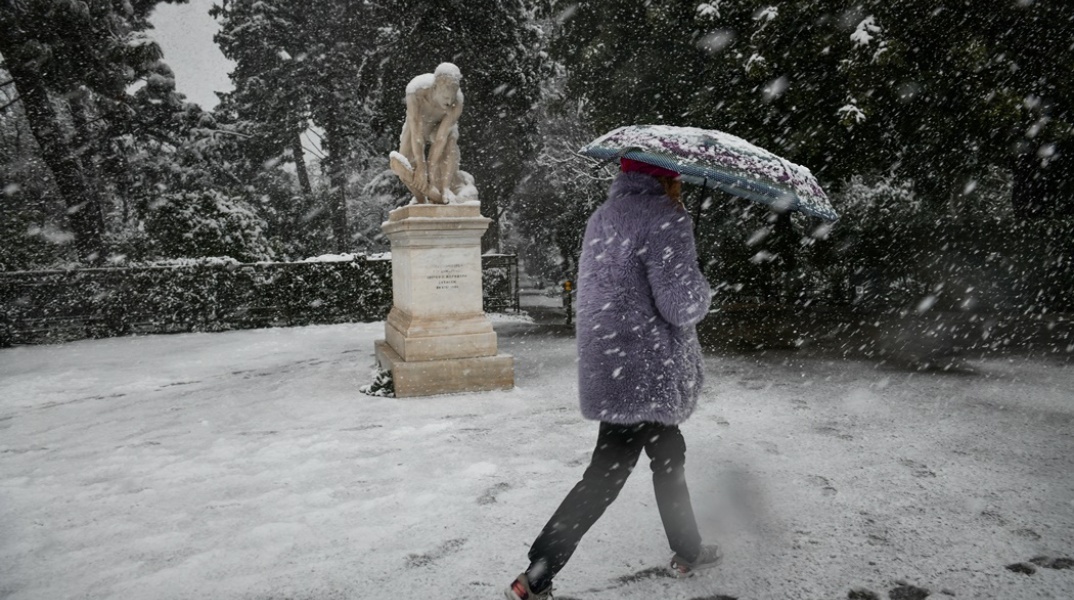 Γυναίκα περπατά με ομπρέλα ενώ χιονίζει 