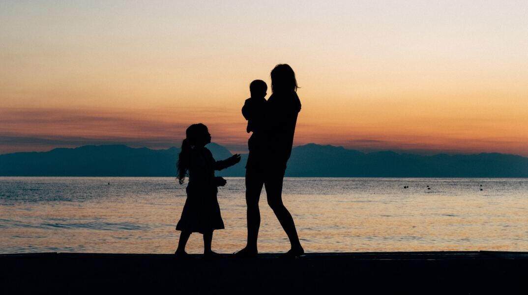 Γυναίκα με δύο παιδιά σε προβλήτα - Διακρίνονται οι σκιές τους κόντρα στη δύση