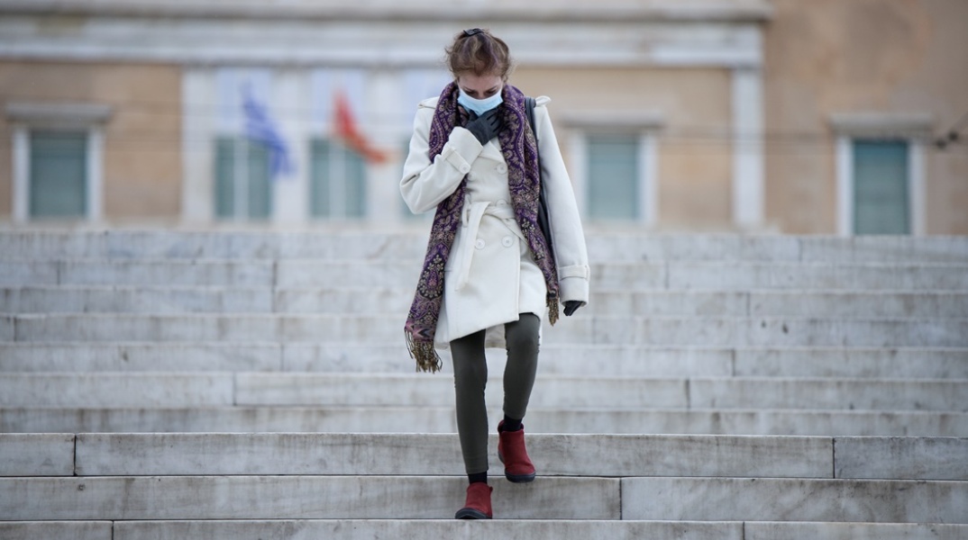 Γυναίκα με μάσκα κατεβαίνει τις σκάλες στην πλατεία Συντάγματος