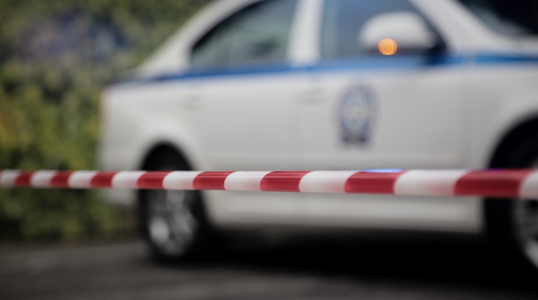 Περιπολικό της ΕΛ.ΑΣ. πίσω από την κορδέλα της αστυνομίας με την οποία έχει αποκλειστεί περιοχή