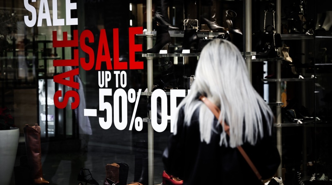 Γυναίκα πλάτη στον φακό μπροστά από κατάστημα υπόδησης με εκπτώσεις 