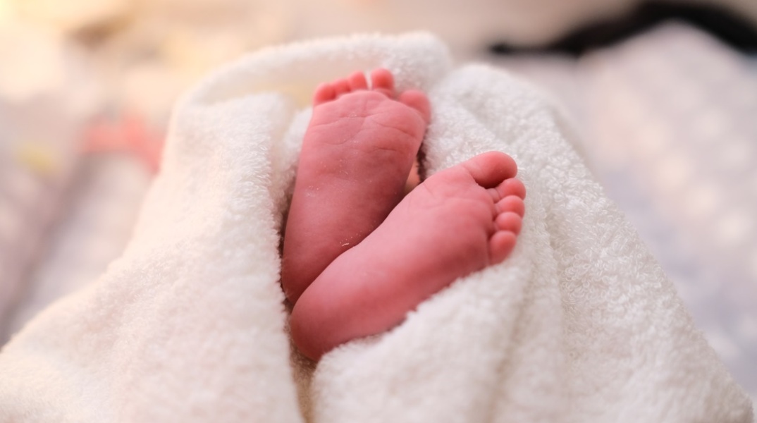 Τα ποδαράκια νεογέννητου μωρού που είναι τυλιγμένο σε πετσέτα
