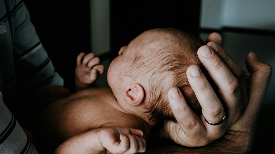 Άτομο κρατά νεογέννητο μωράκι στα χέρια του