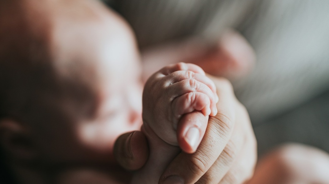 Χεράκι ατόμου κρατά το χεράκι μωρού