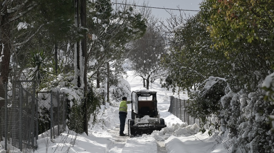 Μηχάνημα για τη διάνοιξη δρόμων από τα χιόνια και δίπλα ο χειριστής του