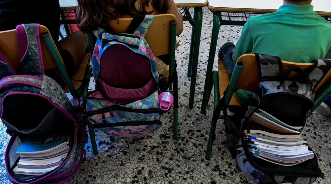 Μαθητές καθισμένοι στις καρέκλες τους και οι ανοιχτές τους τσάντες γεμάτες βιβλία
