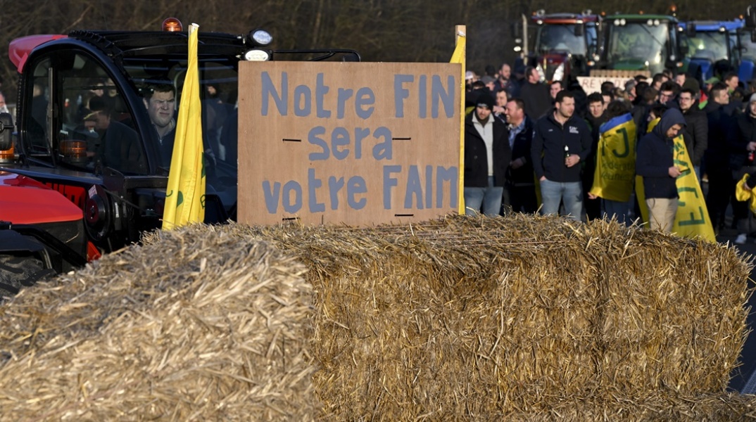 Αγρότες με παραταγμένα τα τρακτέρ τους και σανό σε δρόμο