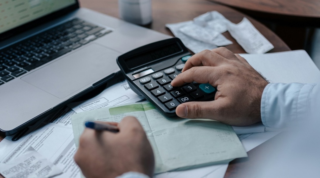 Άτομο κάνει υπολογισμούς και σημειώνει σε χαρτί