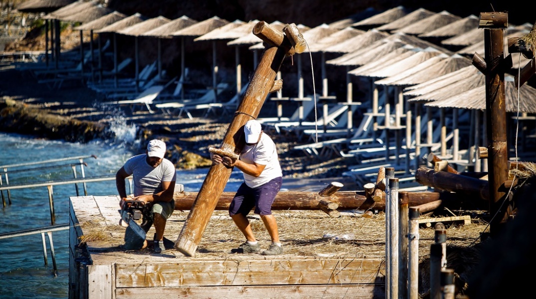 Εργάτες απομακρύνουν κορμούς από παραλία όπου έχει γίνει παραβίαση των χρήσεων γης