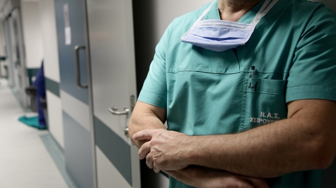 Άτομο με ενδυμασία χειρουργείο με σταυρωμένα χέρια σε διάδρομο νοσοκομείου