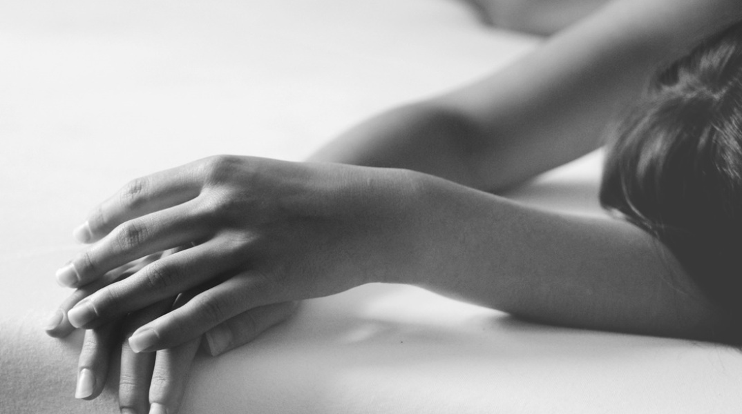 Χέρια γυναίκας πάνω σε κρεβάτι 
