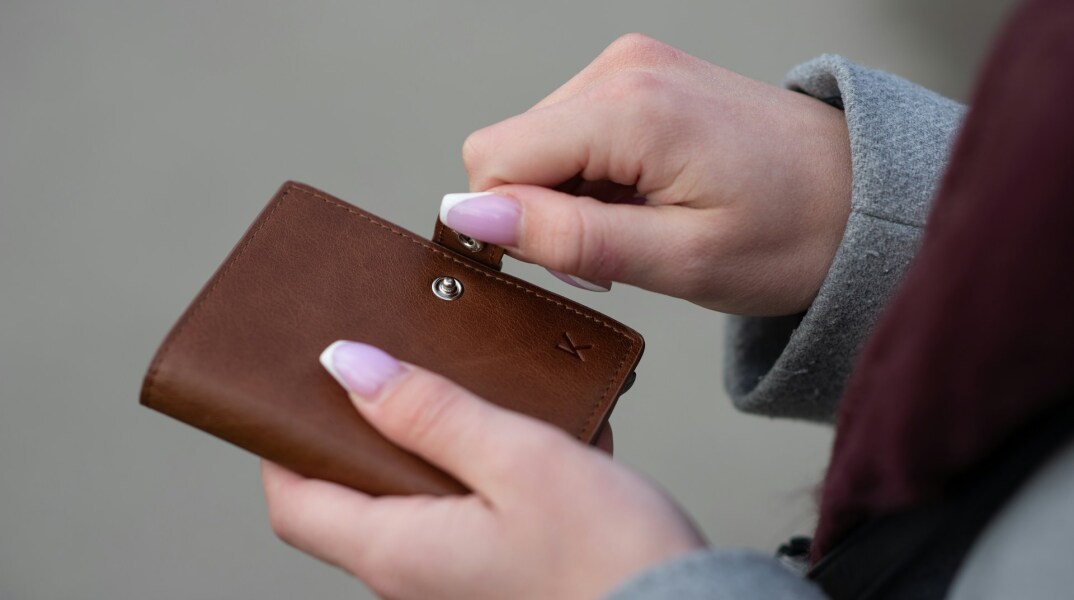 Γυναίκα κρατά στα χέρια της το πορτοφόλι της 
