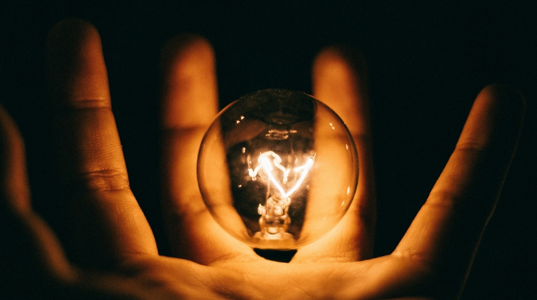 Αναμμένη λάμπα ανάμεσα στα δάχτυλα ατόμου