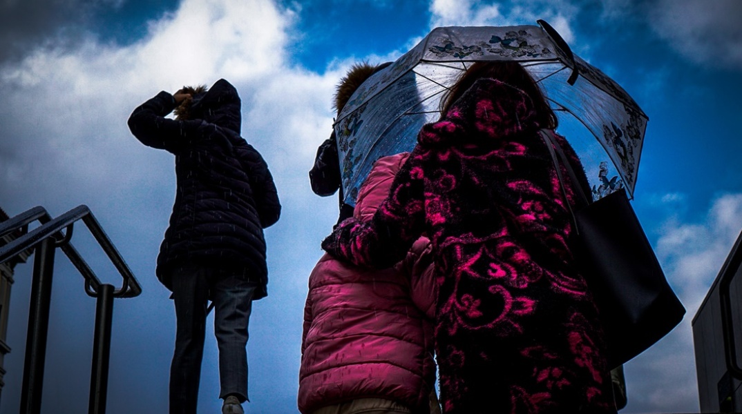 Γυναίκα με ομπρέλα προστατεύεται από ισχυρή βροχόπτωση
