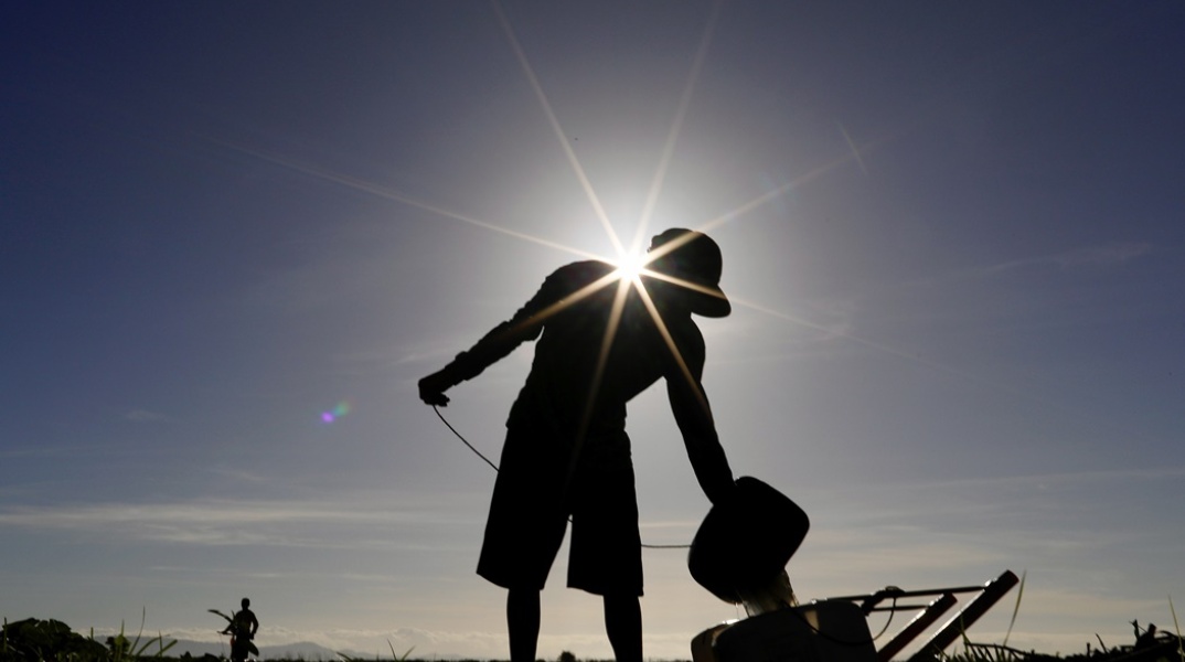 Εργάτης πάνω από μηχάνημα με τον ήλιο κόντρα