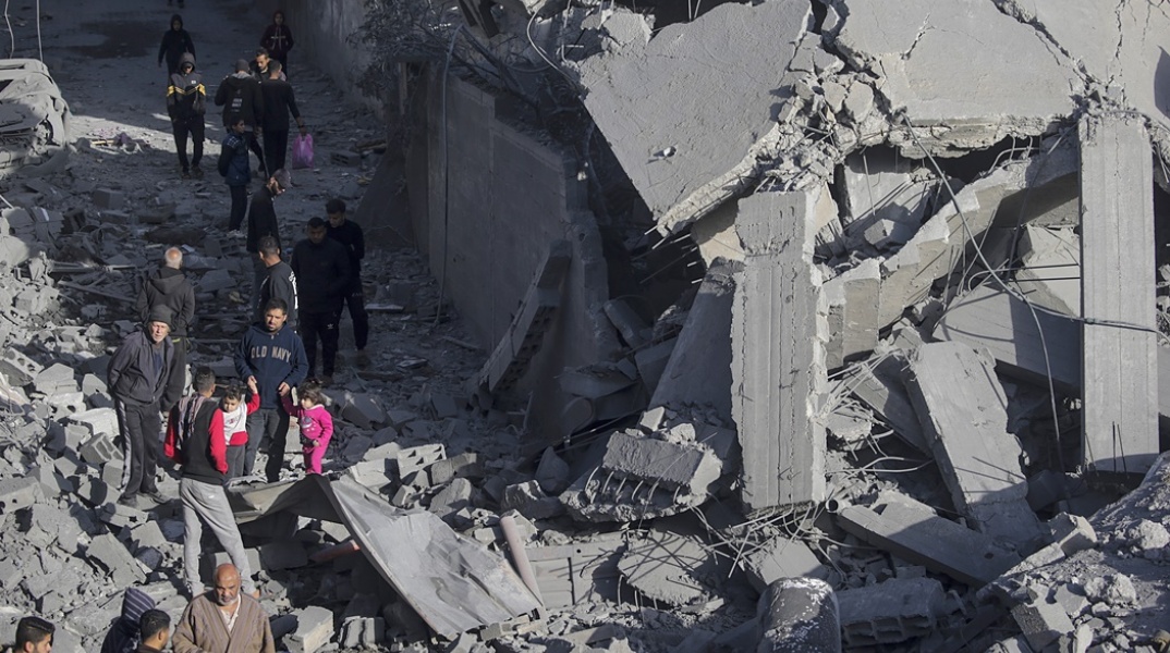 Πολίτες κρατούν από το χέρι μικρά παιδιά, περνώντας από τα συντρίμμια 