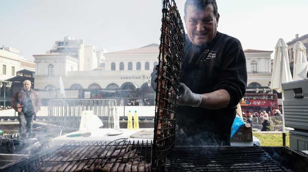 Ψήστης γυρνά τις σχάρες με τα κοψίδια σε υπαίθριο ψήσιμο την Τσικνοπέμπτη