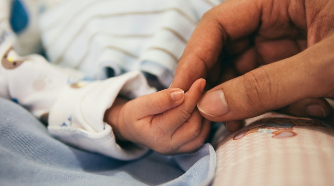 Χέρι κρατά το χεράκι νεογέννητου βρέφους