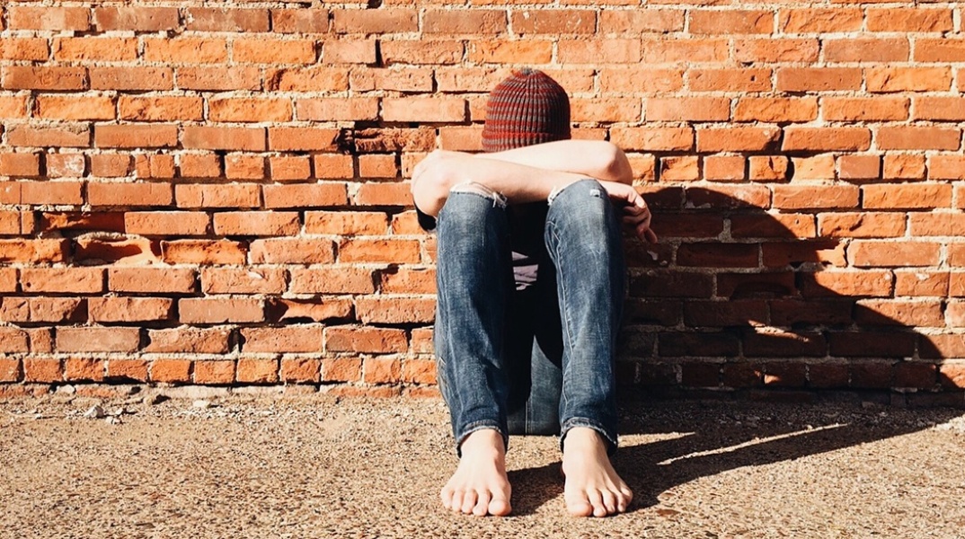 Παιδί που κρατά τα πόδια του με τα χέρια του και κρύβει το πρόσωπό του