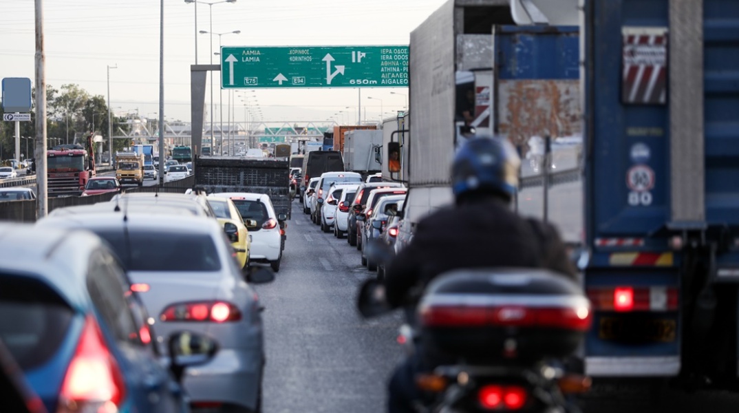 Αυτοκίνητα κολλημένα στην κίνηση και μηχανή που προσπαθεί να περάσει ανάμεσά τους