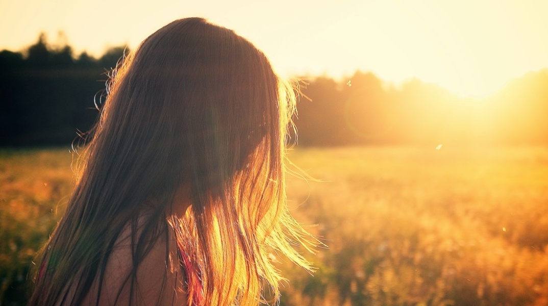 Κορίτσι σε χωράφι με στραμμένο το πρόσωπο προς τον ήλιο